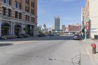 view down city street with buildings in background from corner at center and parking garage on left