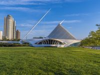 a wide open park filled with green grass next to tall buildings and a river that has many arches
