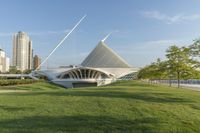 a wide open park filled with green grass next to tall buildings and a river that has many arches