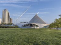 a wide open park filled with green grass next to tall buildings and a river that has many arches
