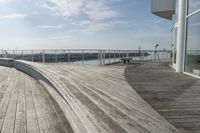 a dock is lined with benches along the water near a beach on a partly sunny day