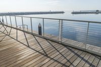 railing along the side of the dock next to the water with boats in the background