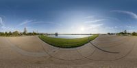 a panoramic image of the ground with trees and water in it and a view of the sun and sky