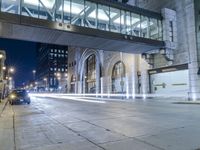 a street with lights and parking meters, in the background is tall buildings and street lights,