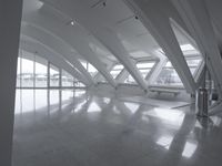 empty white lobby with white marble floor and ceiling tiles, as well as three benches and glass windows