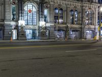 a person riding a bicycle on a city street at night time with some lights on