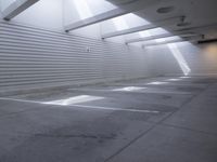 the white wall of an empty parking garage has holes in the concrete and sunlight streaming through