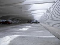 the white wall of an empty parking garage has holes in the concrete and sunlight streaming through