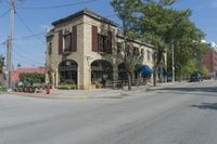 an empty street surrounded by tall buildings and trees in a town with people riding motorcycles