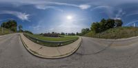 a fisheye lens photo of a view of a street, the sun is shining