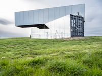 a large mirror sits in the middle of grass outside a building with a sky background