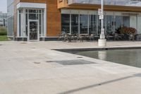 a manhole in the sidewalk beside water features many small potted plants and chairs