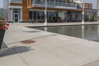 a manhole in the sidewalk beside water features many small potted plants and chairs