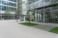 there are some trees and people that are sitting on chairs in the square area of the building