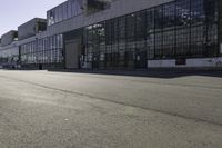 skateboarder riding the street in front of a large building with many windows and doors