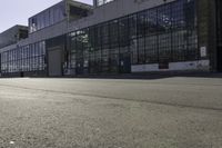 skateboarder riding the street in front of a large building with many windows and doors