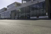 skateboarder riding the street in front of a large building with many windows and doors