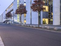 an empty street with a big white building in the background at dusk, on the side