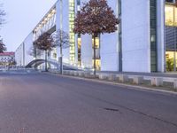 an empty street with a big white building in the background at dusk, on the side