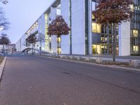 an empty street with a big white building in the background at dusk, on the side