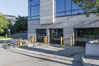 there is a large parking lot on the sidewalk by the building with yellow poles in front