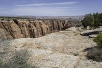 an area with a big canyon and mountains in the background, with a single person walking along it