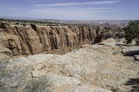 an area with a big canyon and mountains in the background, with a single person walking along it