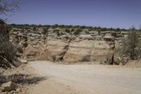 dirt road going through an otherwise arid terrain with a clear blue sky overhead as seen from above the area