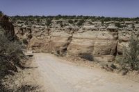 dirt road going through an otherwise arid terrain with a clear blue sky overhead as seen from above the area