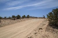 a motorcycle on a dirt road in the desert area of a country setting with a blue sky