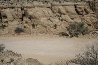 a motorcycle driving through a sandy desert canyon road with tall rock walls in the background