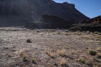 a field full of dry grass in front of mountain tops and hills, which is the sun rising