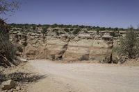 a road in the desert with large rocky sides and greenery on both sides of it