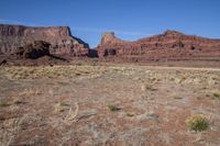 a barren landscape is shown on a clear day outside of the canyon, a large rock formation is visible