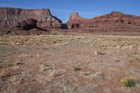 a barren landscape is shown on a clear day outside of the canyon, a large rock formation is visible