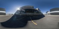 a fish eye lens image of an airport with the sun shining on the ground and a few large buildings