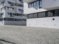 a brick driveway is next to a modern apartment building with two floors, with several windows