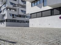 a brick driveway is next to a modern apartment building with two floors, with several windows