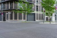 an apartment building with a large front door sits next to an empty street and trees