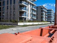 view from behind the orange railing of an apartment building with a street view to the distance