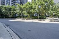 a car driving down an empty street lined with tall buildings and trees in the background