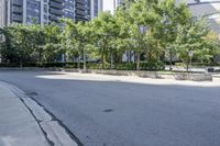 a car driving down an empty street lined with tall buildings and trees in the background