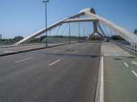 a truck driving across a bridge near a street corner near buildings and a bridge with many cables