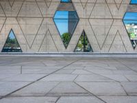 a person walking in front of an architectural building with windows and geometric designs on it