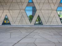 a person walking in front of an architectural building with windows and geometric designs on it