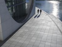 a large cement building next to water with sun shining in it's reflection on the glass wall