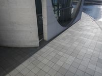 a large cement building next to water with sun shining in it's reflection on the glass wall