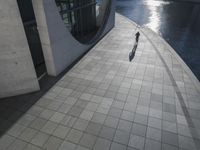 a large cement building next to water with sun shining in it's reflection on the glass wall