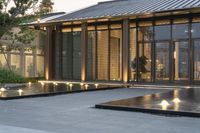 lighted water features and courtyard seatings with green trees in the background for an architectural outdoor space