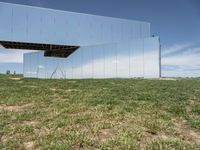 a large mirror is sitting in a grassy field by some rocks and the sky with white clouds